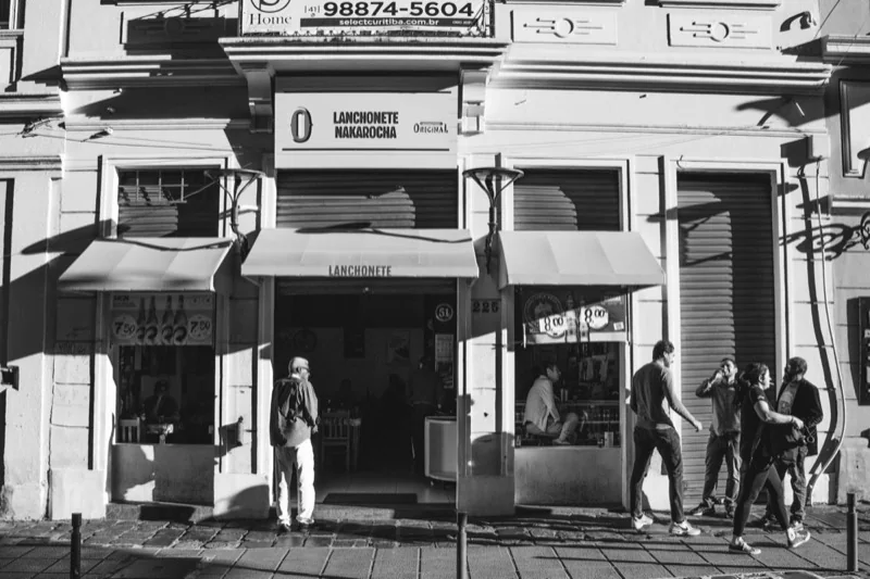 exterior of a building with a bar and people walking on the pavement — illustrative editorial photography, not a verified location