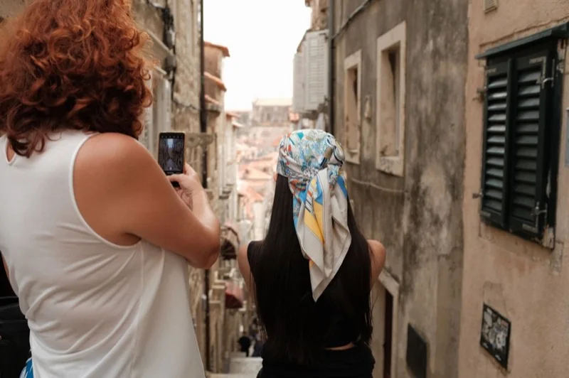 women taking photos in a narrow steep old town alley in dubrovnik croatia — illustrative editorial photography, not a verified location