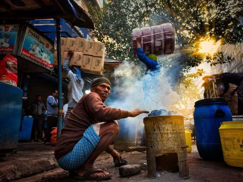 man making a fire in a barrel — illustrative editorial photography, not a verified location
