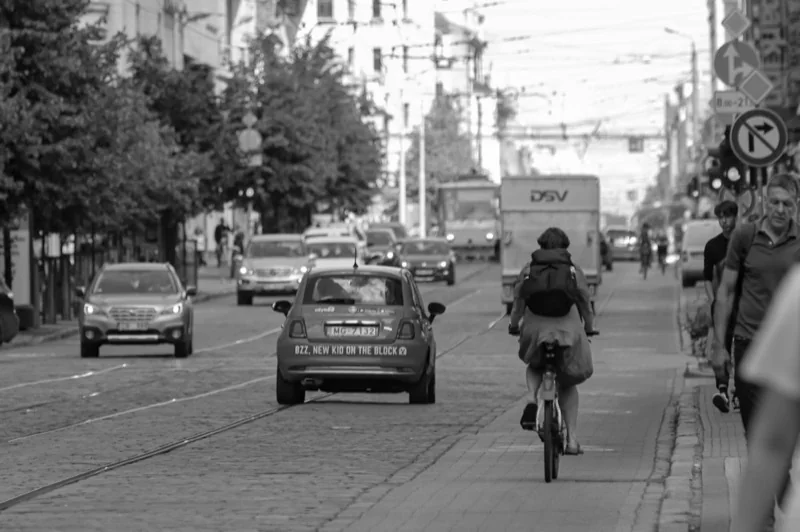 busy city road with moving cars and pedestrians on sidewalk — illustrative editorial photography, not a verified location