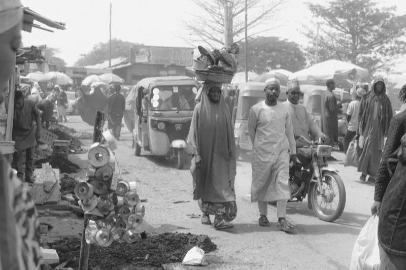 people on street in village in black and white — illustrative editorial photography, not a verified location