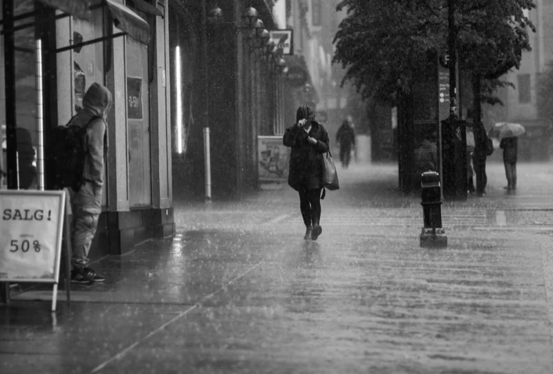people walking on a city street under rain — illustrative editorial photography, not a verified location
