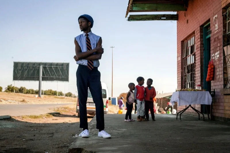 black serious man in stylish outfit standing on roadside — illustrative editorial photography, not a verified location
