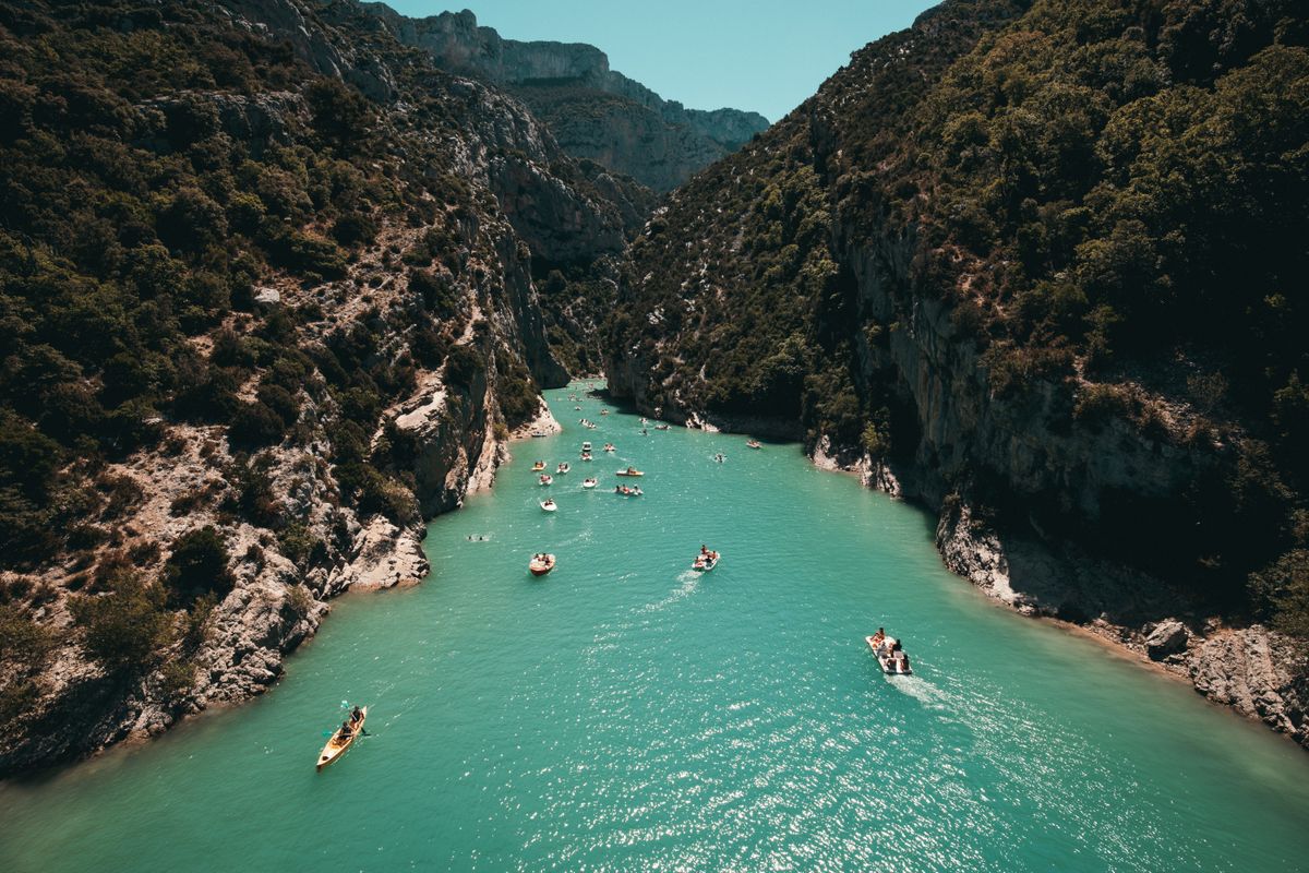 Kayakers on turquoise water between canyon walls